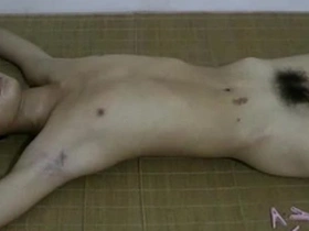 Young Asian man in BDSM bondage suffers as he has clips attached to his body.